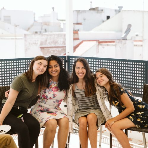 Diverse group of women sitting on a bench smiling.