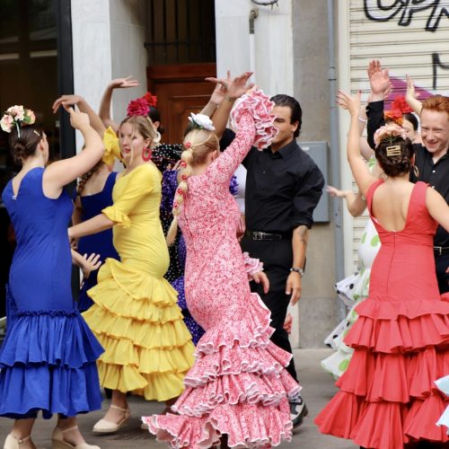 Colorful group of women and men Flamenco dancing in vibrant colored flamenco dresses.