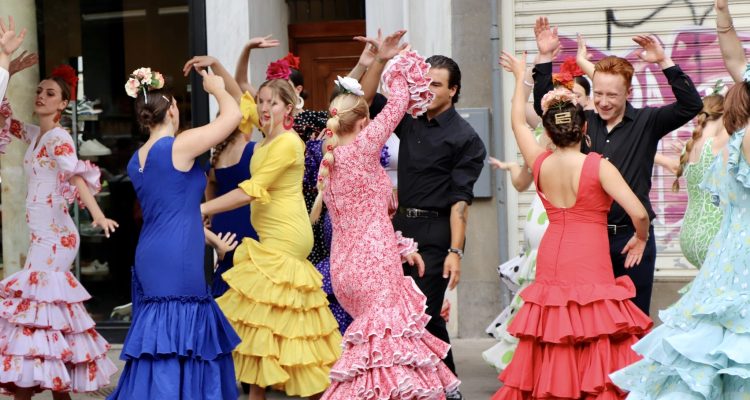 Colorful group of women and men Flamenco dancing in vibrant colored flamenco dresses.